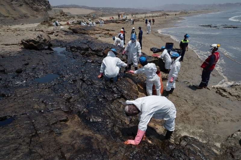 Workers on a Peruvian beach clean up an oil spill caused by abnormal waves triggered by a massive underwater volcanic eruption h
