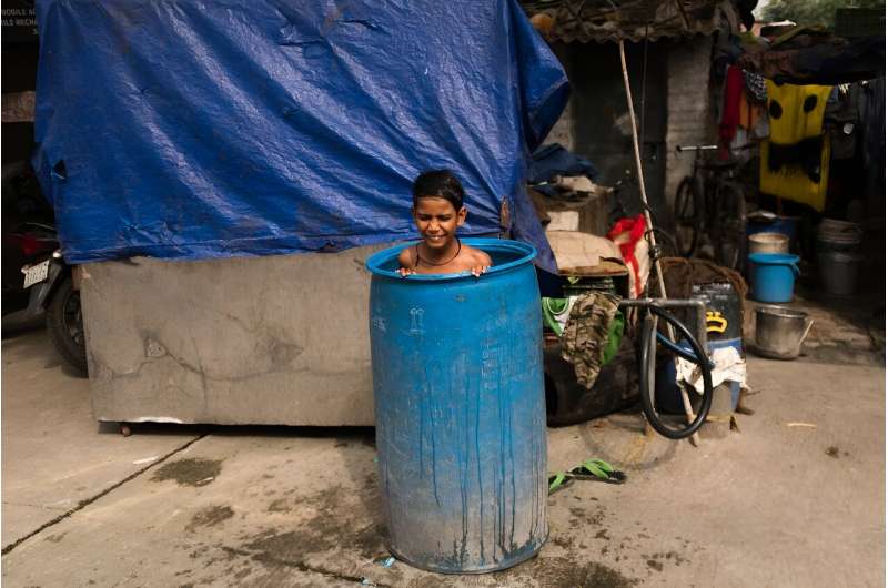A boy cools off inside a barrel filed with water during a hot summer day in New Delhi