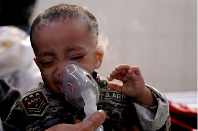 A boy with breathing difficulties reacts as his mother helps him use a nebuliser in a crowded New Delhi hospital