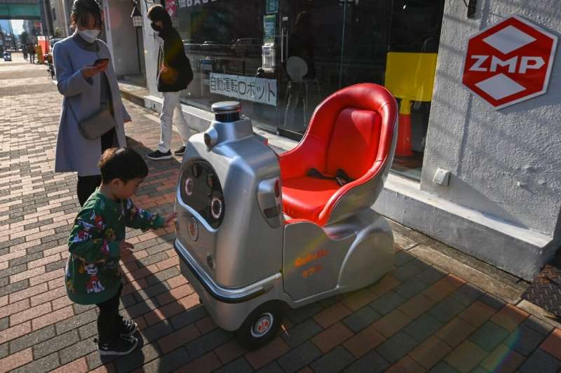 A child and his mother look at a mobility robot RakuRo, developed by Tokyo-based robotics firm ZMP, at the company's service sta