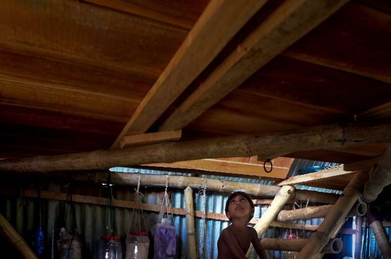 A child climbs a ladder inside a mobile modular shelter -- Khudi Bari, or tiny house -- in a Bangladeshi village