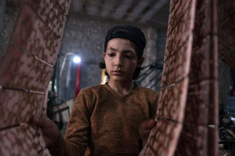 Un niño trabajador clasifica esteras y alfombras hechas de plástico reciclado en una fábrica en Sarmada.