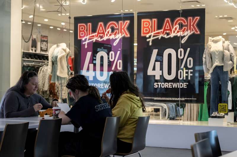 A family eats lunch near a store advertising a Black Friday sale at the Pentagon City Mall in Arlington, Virginia