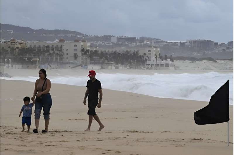 A family walks on the beach in the Mexican tourist resort of Cabo San Lucas before the arrival of Hurricane Hilary