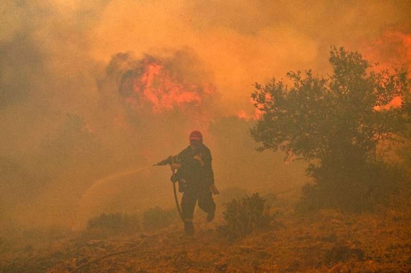 A firefighter tries to control a blaze in New Peramos, near Athens on July 19