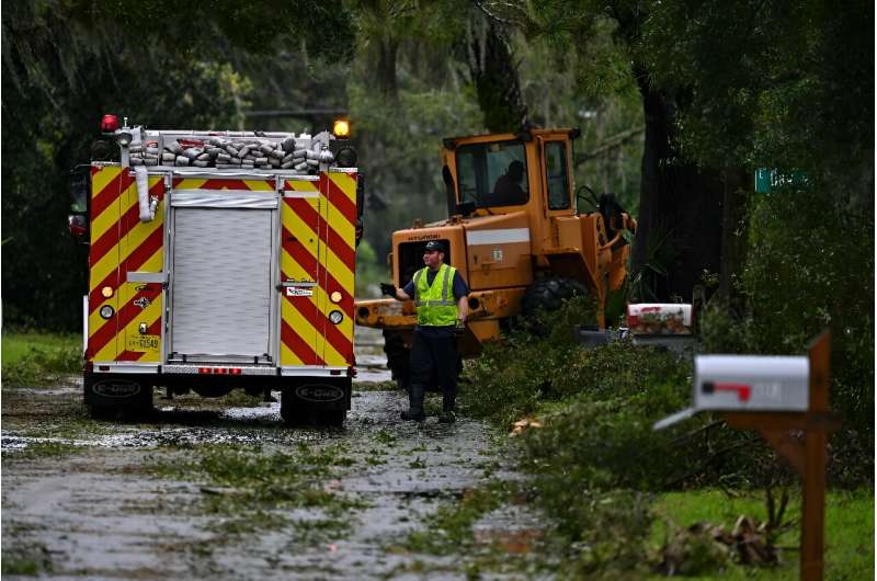A first responder clears debris off the street in Perry, Florida after Hurricane Idalia slammed into the coast as a powerful Cat