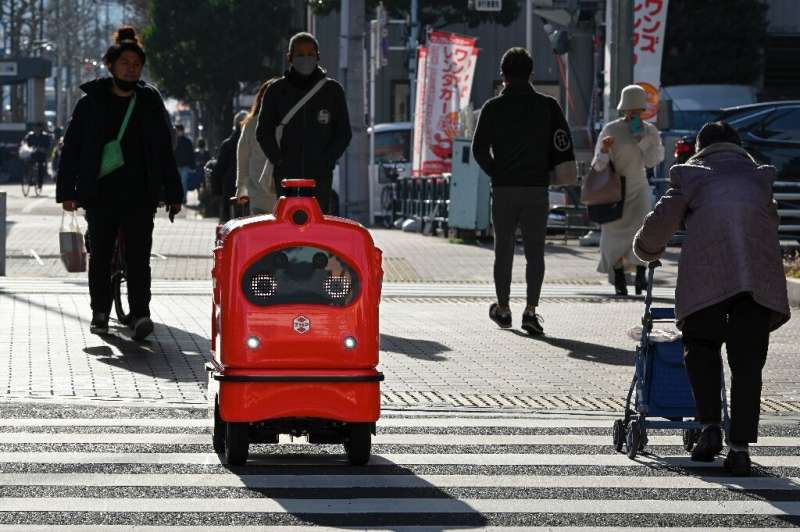 A four-wheeled robot dodges pedestrians on a street outside Tokyo, part of an experiment businesses hope will tackle labour shor