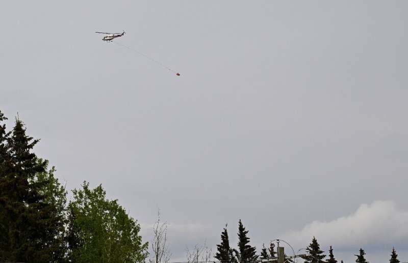 A helicopter carrying a &quot;Bambi Bucket&quot; flies toward a forest fire near the town of Drayton Valley in Canada's Alberta 