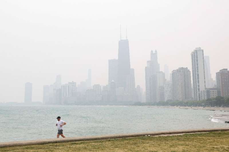 A jogger runs along the shoreline of Lake Michigan with heavy smoke from the Canadian wildfires covering the city of Chicago in 