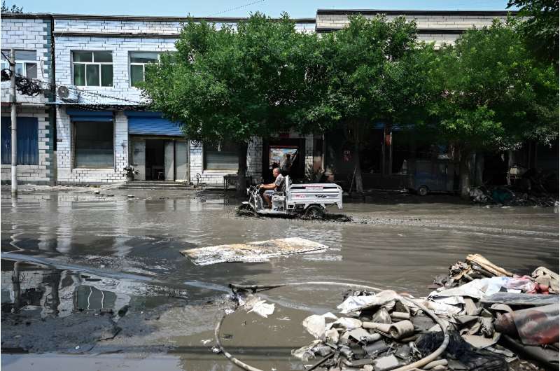 A man drives along a flooded street in the aftermath of flooding from heavy rains in Zhuozhou city, in northern China's Hebei pr