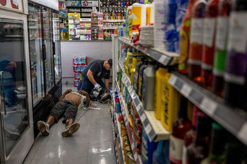 A man is given medical aid after collapsing from the heat in a Phoenix supermarket in July 2023 in Arizona