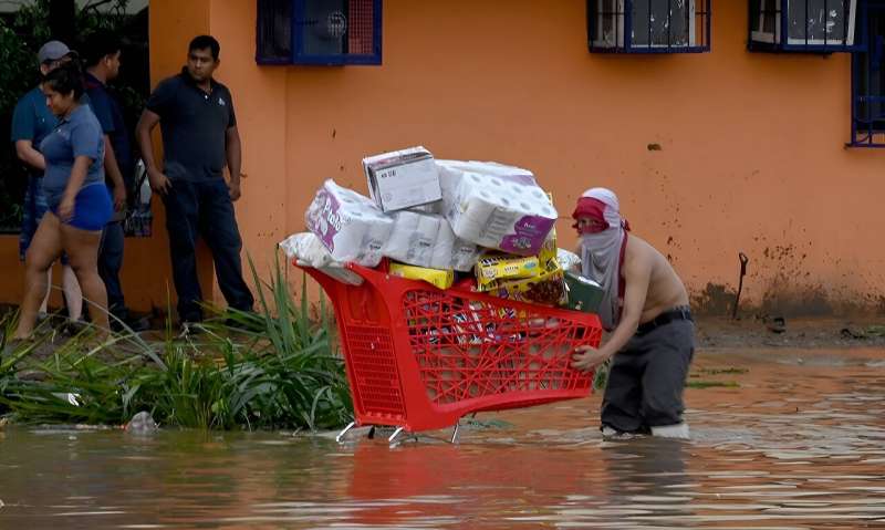 A man pushes a shopping cart of goods from a looted supermarket in Mexico's hurricane-stricken city of Acapulco