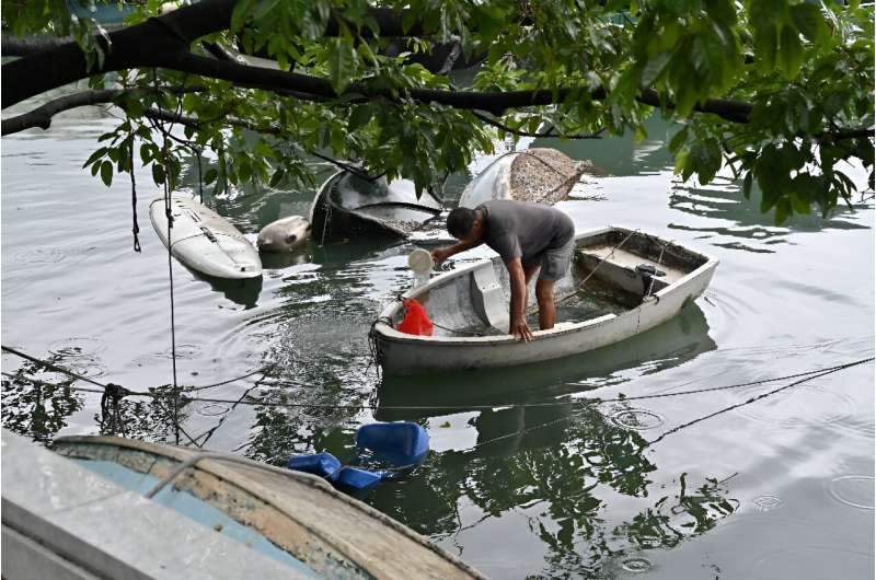 A man removes rainwater accumulated in his boat by Typhoon Saola at Victoria Harbour in Hong Kong