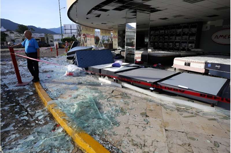 A man stands next to a mattress store damaged by Hurricane Lidia in the Mexican beach resort of Puerto Vallarta