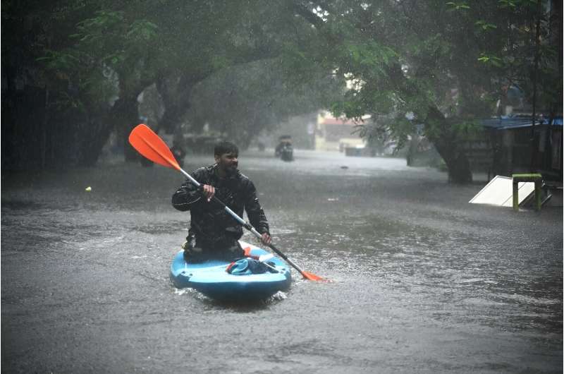 A man uses a kayak to cross a flooded street after heavy rains in Chennai