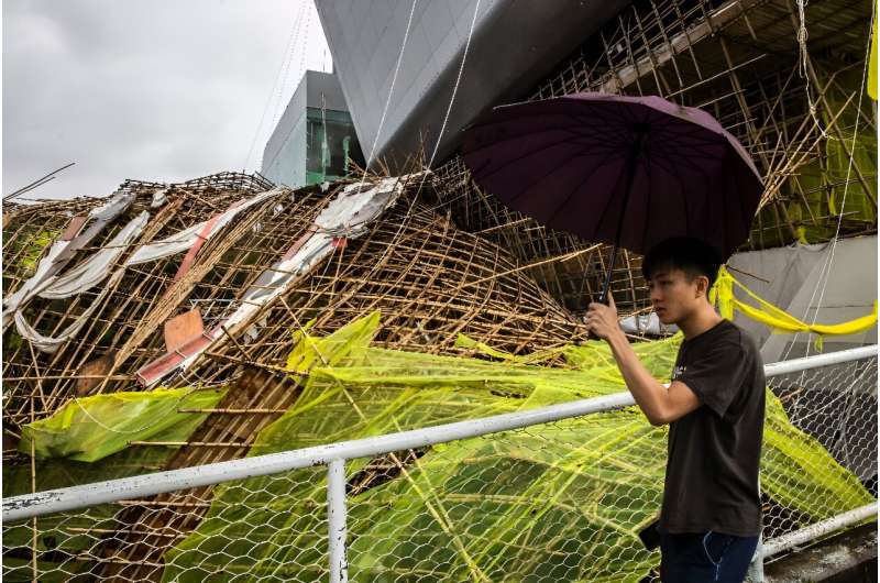 A man walks past bamboo scaffolding that has been brought down by Typhoon Saola at Kowloon Tong in Hong Kong