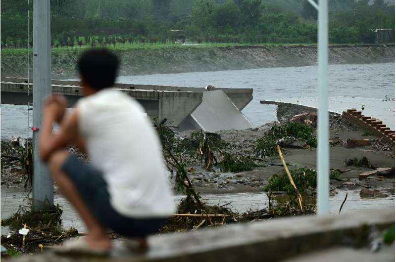 A man watches a collapsed bridge on the Dashihe River after heavy rains