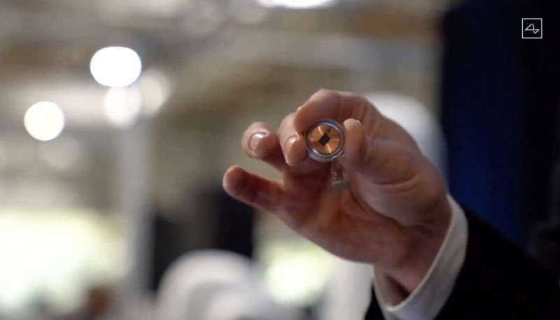 A Neuralink disk implant held by Elon Musk