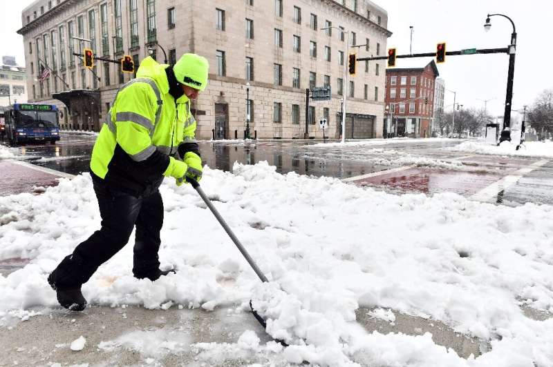 A person clears snow from the sidewalk in Worcester, Massachusetts on March 14, 2023