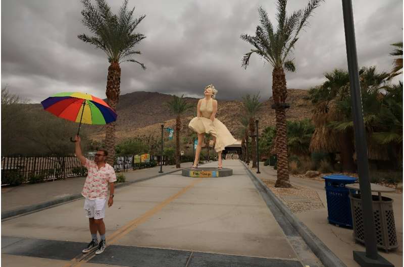 A person holds an umbrella in front of the &quot;Forever Marilyn&quot; statue, designed by US artist John Seward Johnson II, in 