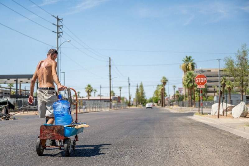 A person transports a water jug through a neighborhood in Phoenix, Arizona, on July 14, 2023