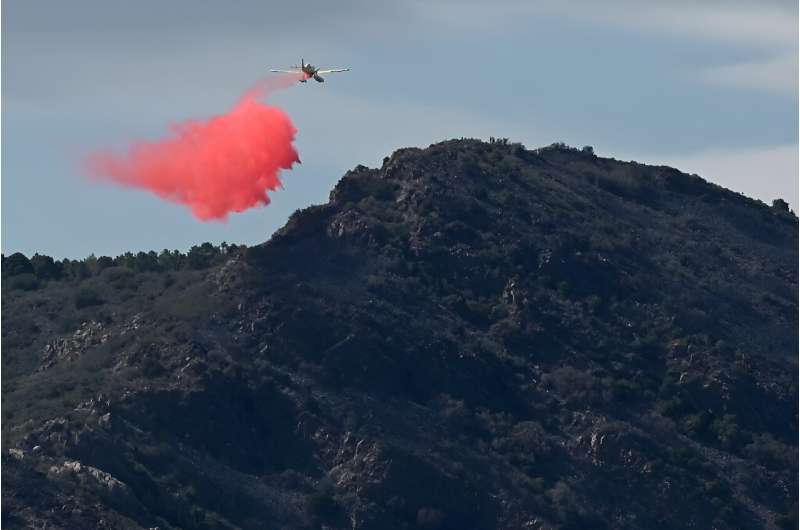 A plane sprays fire retardant over the wildfire south of Portbou