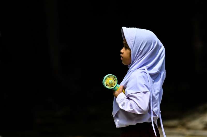 A primary school student uses a portable fan to keep cool during hot weather in Banda Aceh, Indonesia, on May 15, 2023