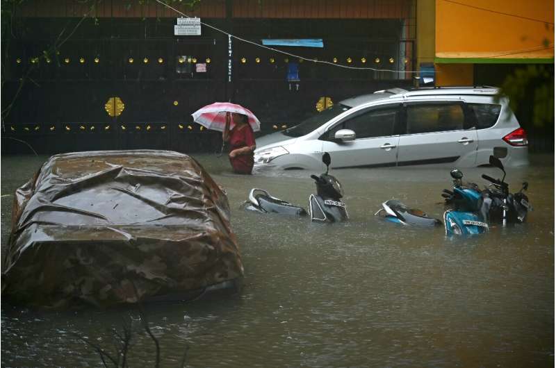 A resident wades through a flooded street after heavy rains in Chennai on December 4
