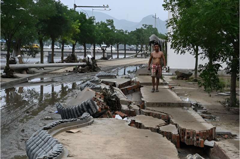 A resident walks on a broken wall after flooding battered swathes of northern China