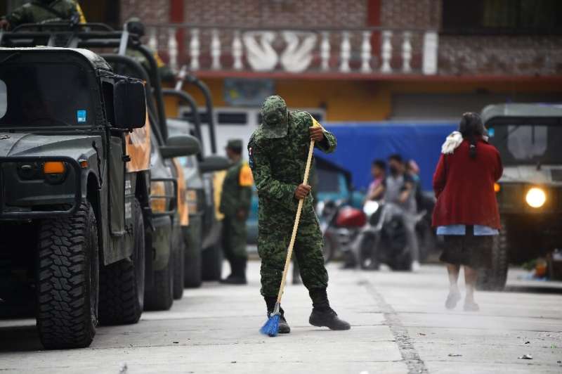 Солдат подметает пепел на улице в городе недалеко от вулкана Попокатепетль в Мексике.