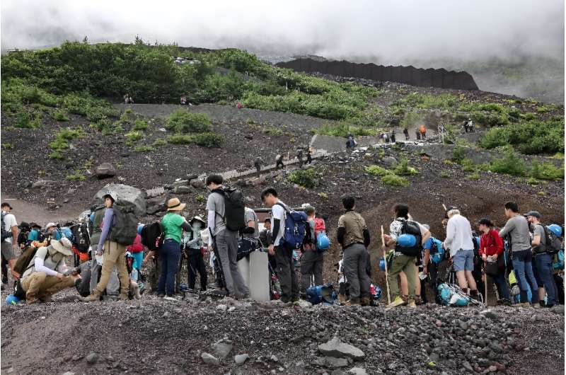 A stream of people trudges through the volcanic grit on their way up the 3,776-metre mountain