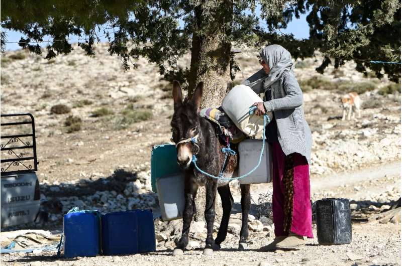 A Tunisian farmer transports water she filled up from a river on the back of a donkey in the remote village of Ouled Omar