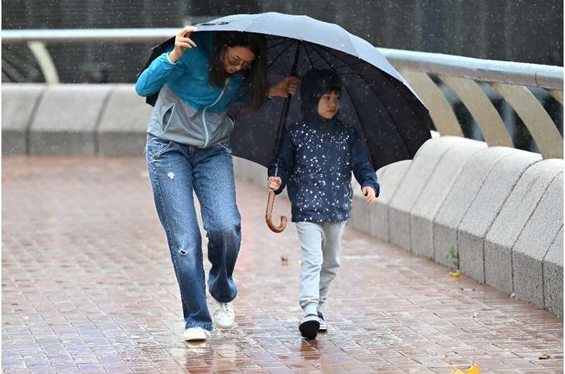 A woman and a child struggle with strong winds in Hong Kong on October 8, 2023 as typhoon Koinu skirted by