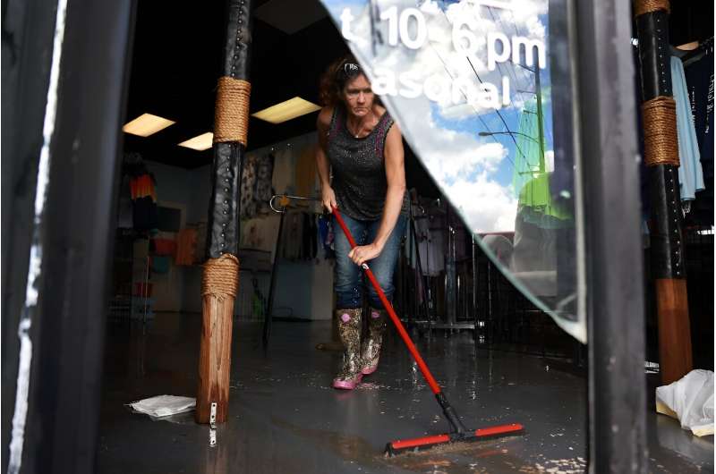 A woman squeegees water out of a shop in Crystal River, Florida following Hurricane Idalia