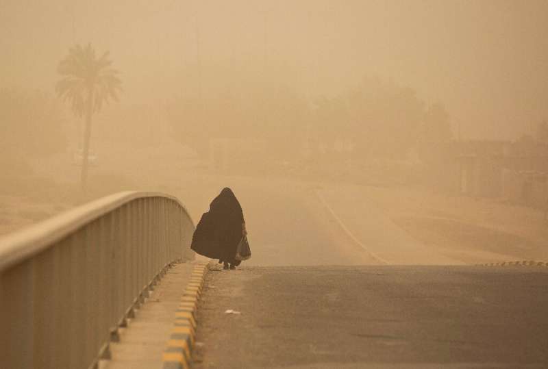 A woman walks along a bridge during a sandstorm in Iraq's southern city of Basra, on June 26, 2022
