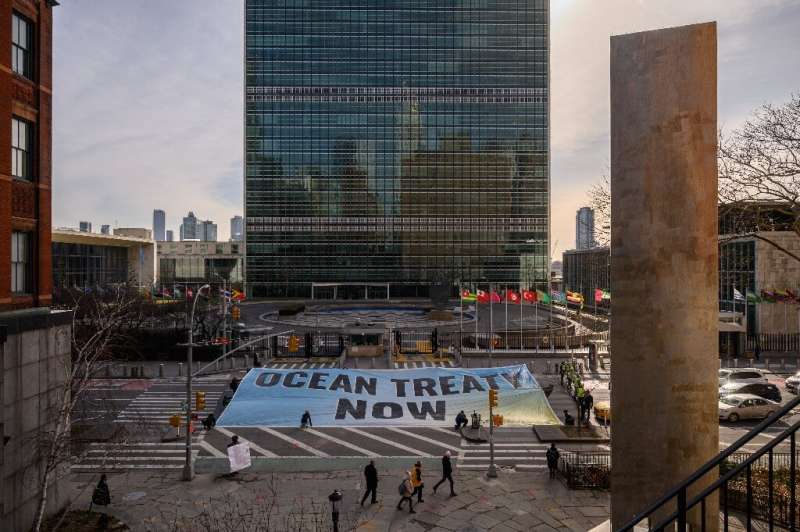 Activists from Greenpeace display a banner outside the United Nations headquarters during negotiations on a treaty to protect th