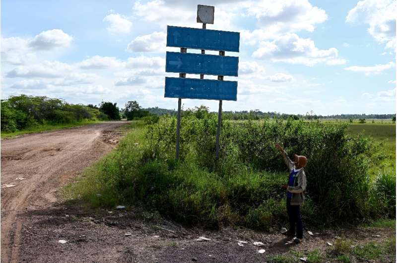 An activist gestures towards old signs for a sugarcane company at the site of an economic land concession in Cambodia's Preah Vihear province