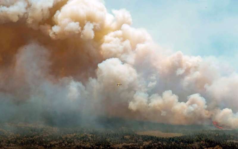An aircraft from New Brunswick drops a mix of water and fire retardant over the fire near Barrington Lake, Shelburne County, Can
