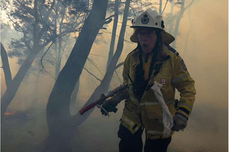 An Australian firefighting volunteer gasps for air while moving out of an area with thick smoke during a hazard reduction burn