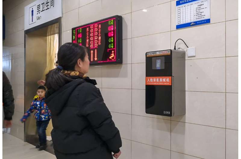 An automatic toilet paper dispenser (R) at a Chinese railway station uses facial recognition technology. China is drafting rules