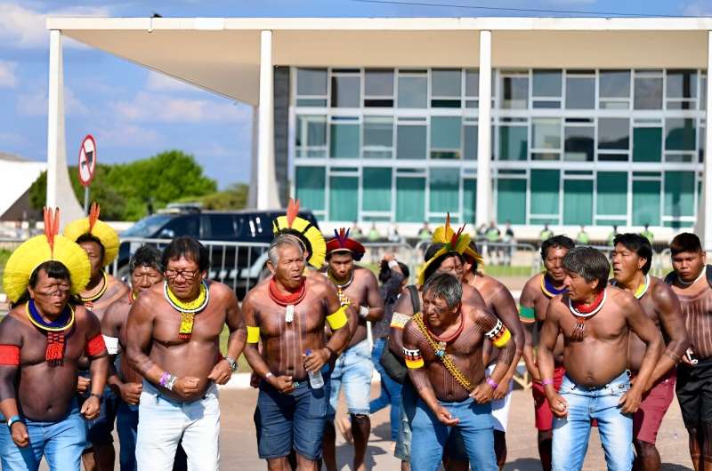 Brazilian Indigenous men outside the Supreme Court in Brasilia celebrate as the court rule against efforts to restrict native peoples' rights to reservations on their ancestral lands