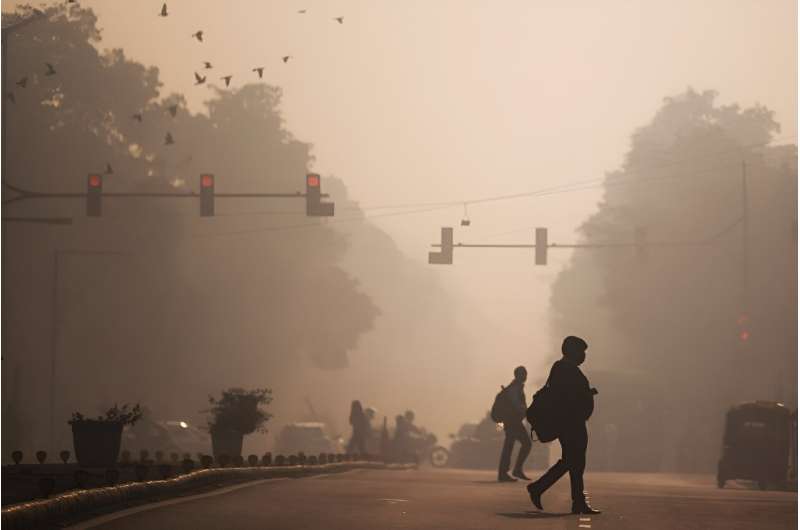 Commuters cross a street amid smoggy conditions in New Delhi in November 2021