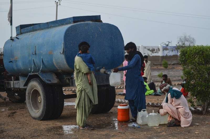 Cyclone evacuees collect water from a tanker outside a temporary shelter set at a school in Badin district of Pakistan's Sindh p