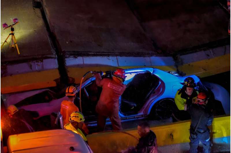 Emergency workers attempt to rescue people trapped in a car under a wall that collapsed due to heavy rains, in in Santo Domingo, Dominican Republic, November 18, 2023