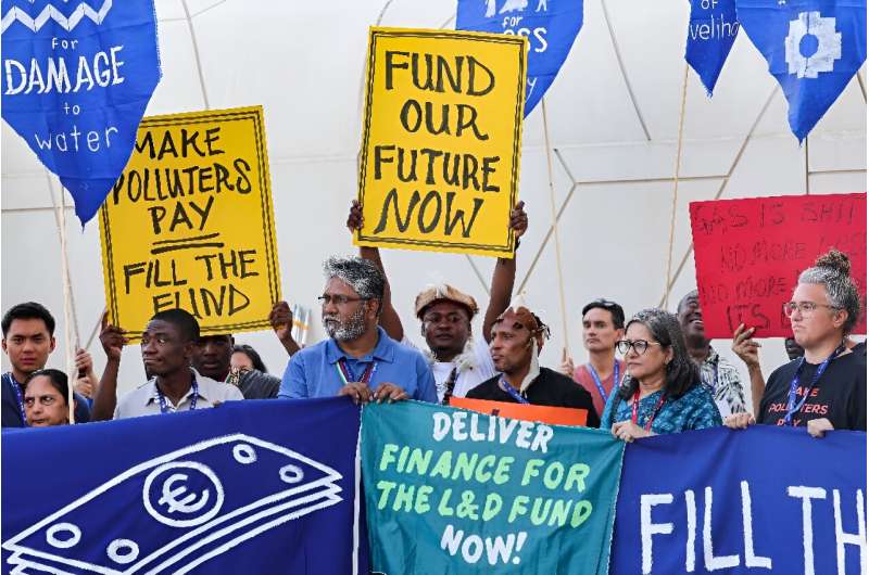 Environmental activists display placards during a demonstration at the venue of the COP28 United Nations climate summit in Dubai