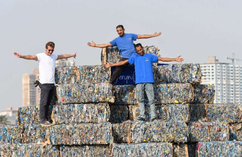 Environmental volunteers stand atop a pyramid of compressed plastic waste collected from the Nile, in Giza near the capital on &
