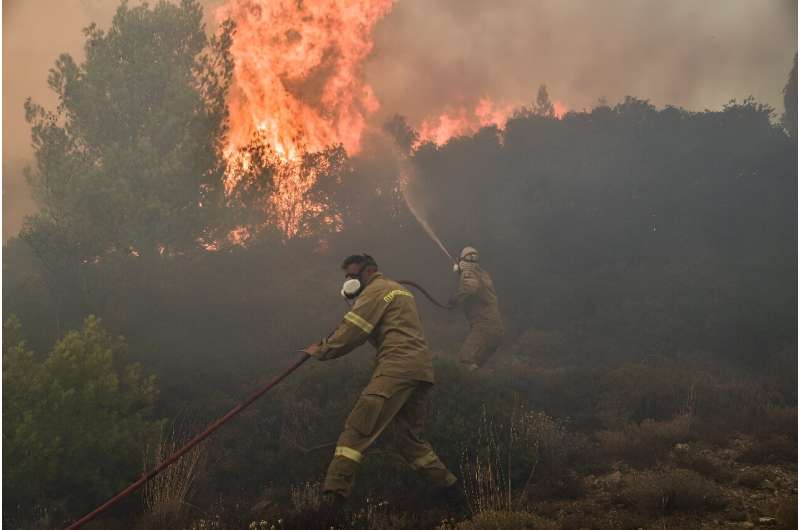 Firemen battle flames during a wildfire near Prodromos, 100km northeast from Athens