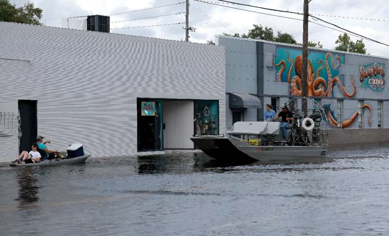 Kayakers and an airboat cruise down a flooded street after Hurricane Idalia passed offshore in Crystal River, Florida