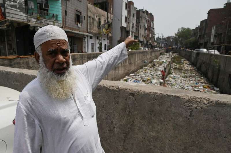 Khalil Ahmad, a resident of New Delhi's Seelampur neighbourhood, gestures towards a sewage canal filled with garbage during a in