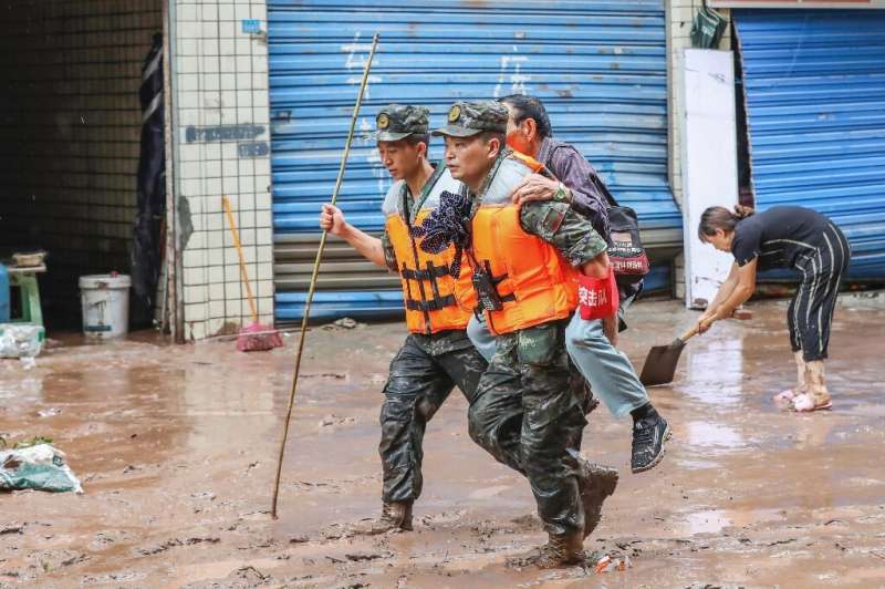 Paramilitary policemen evacuate a resident after flooding in Chongqing